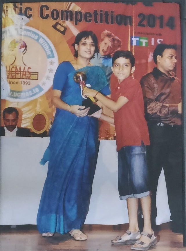 Kavish as a child receiving a trophy on stage at an abacus competition in 2014